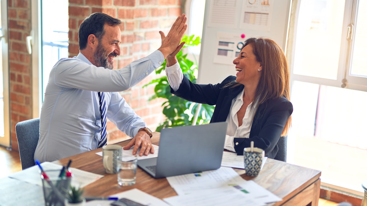Business professionals celebrating a successful placement in a modern office